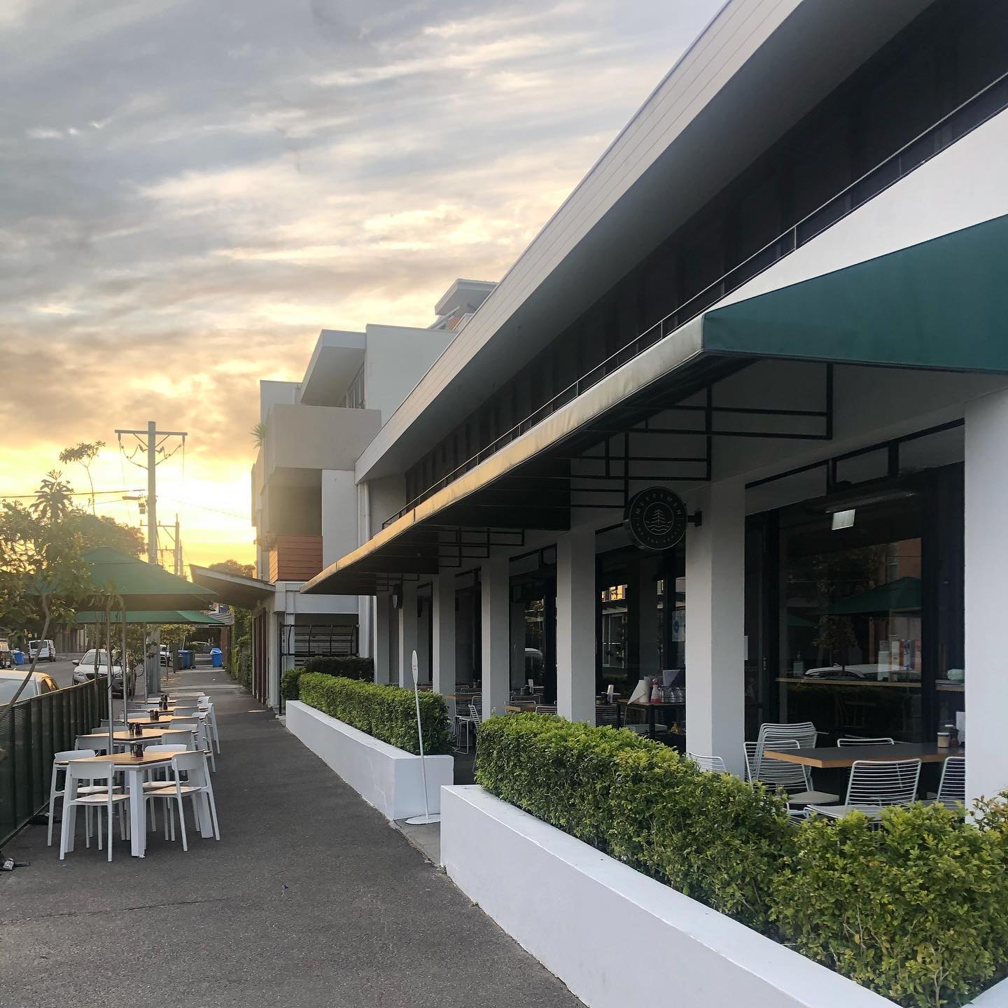 The footpath tables under the green awning at sunset