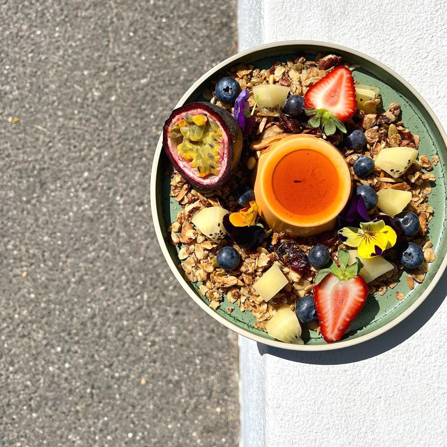 A granola bowl with passionfruit, strawberries and blueberries, from above