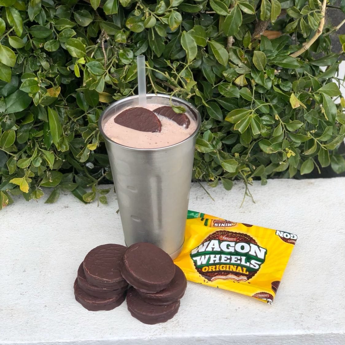A Wagon Wheels milkshake in a steel cup next to the biscuits