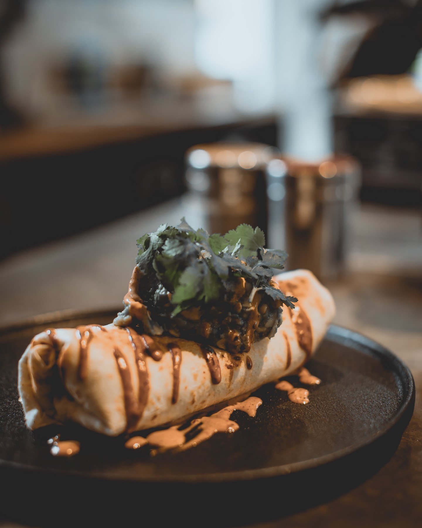 Brekky burrito on a dark plate with chipotle mayonnaise and herbs