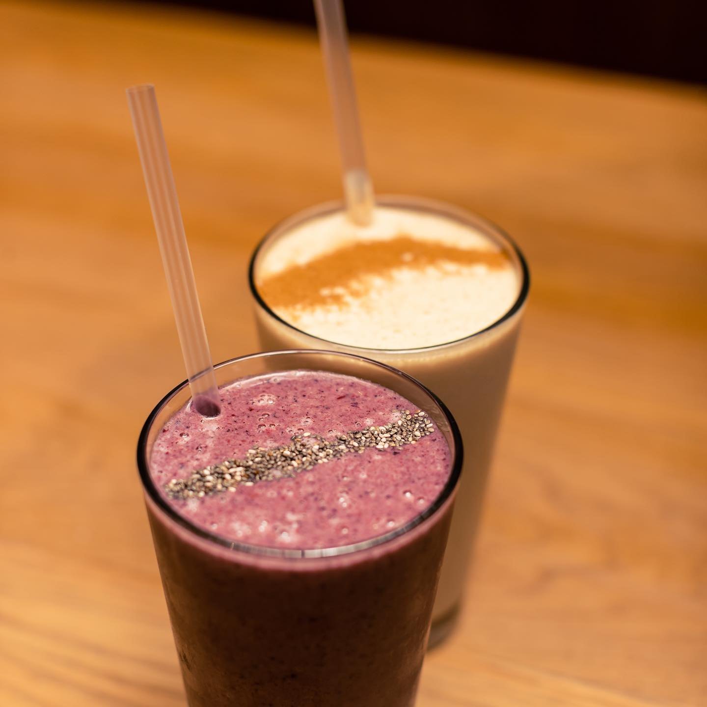 A berry smoothie and an iced coffee on a timber table